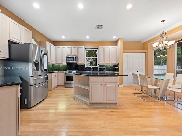 kitchen with light wood finished floors, appliances with stainless steel finishes, visible vents, and decorative backsplash