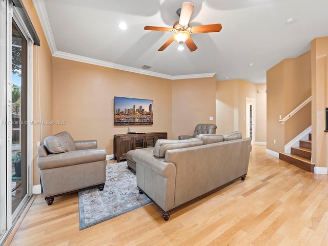 living room featuring crown molding, baseboards, stairs, and light wood-style floors