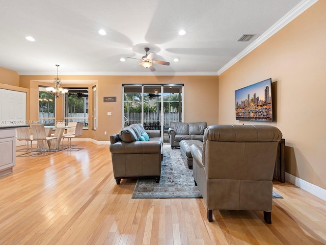 living area with a healthy amount of sunlight, light wood-style flooring, visible vents, and crown molding