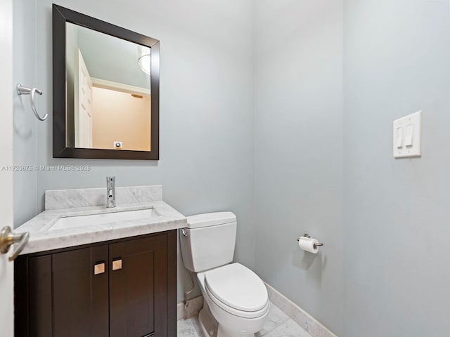 bathroom with baseboards, vanity, and toilet