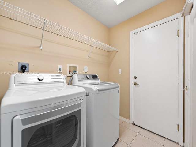 clothes washing area featuring laundry area, light tile patterned flooring, and washing machine and clothes dryer