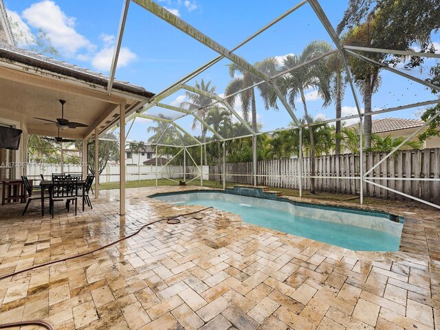 view of swimming pool with a lanai, a fenced backyard, a patio, and ceiling fan