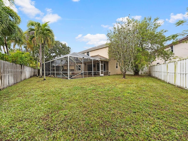 view of yard with glass enclosure and a fenced backyard