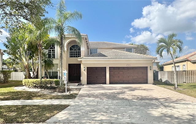 mediterranean / spanish-style home featuring a garage, driveway, and fence