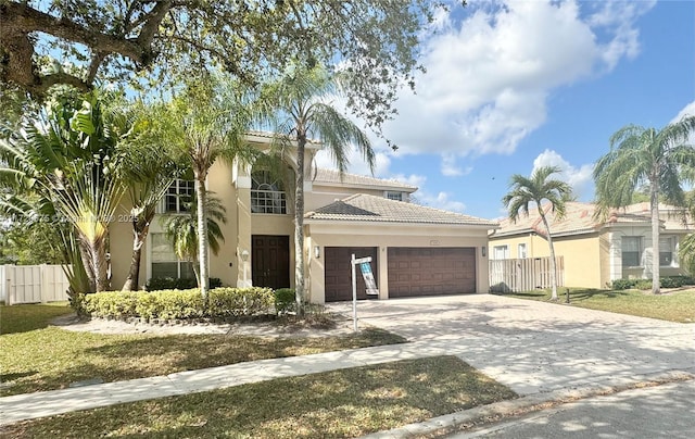 mediterranean / spanish home with a garage, fence, driveway, a tiled roof, and stucco siding