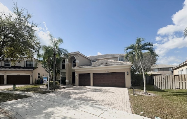 view of front facade with a garage, fence, a tiled roof, decorative driveway, and stucco siding