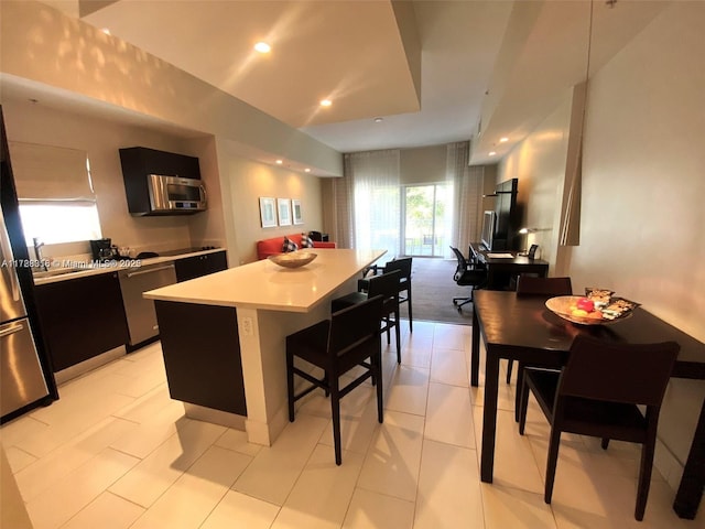 kitchen with a kitchen breakfast bar, appliances with stainless steel finishes, and a center island