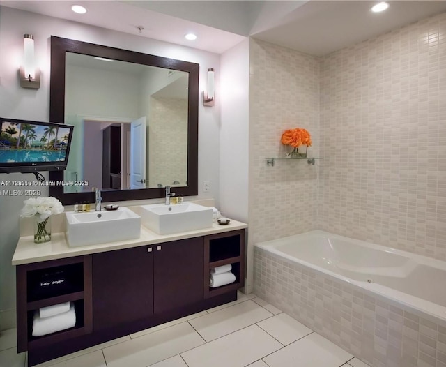 bathroom featuring tiled bath, vanity, and tile patterned flooring