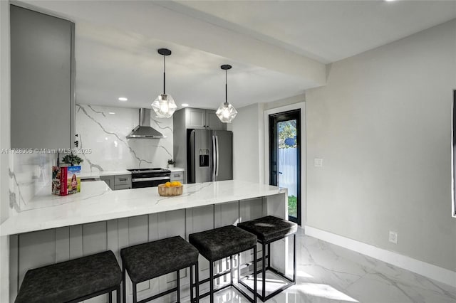 kitchen featuring wall chimney range hood, stainless steel appliances, a kitchen breakfast bar, kitchen peninsula, and gray cabinetry