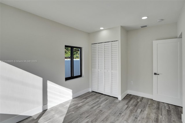 unfurnished bedroom featuring light hardwood / wood-style floors and a closet