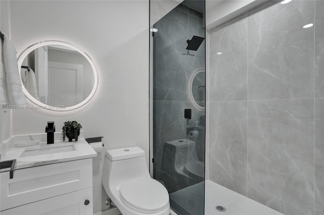 bathroom with toilet, vanity, and tiled shower