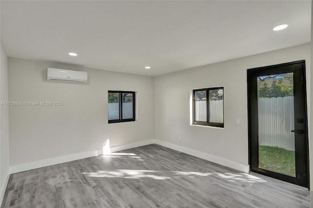 unfurnished room featuring light hardwood / wood-style flooring and a wall unit AC