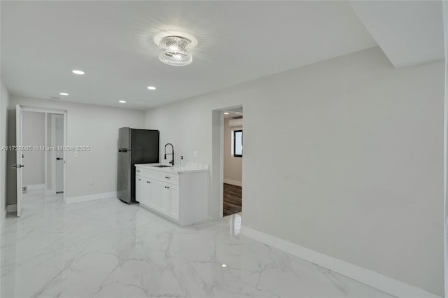 kitchen with sink, stainless steel refrigerator, and white cabinetry