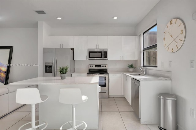 kitchen featuring appliances with stainless steel finishes, white cabinetry, a kitchen island, and sink