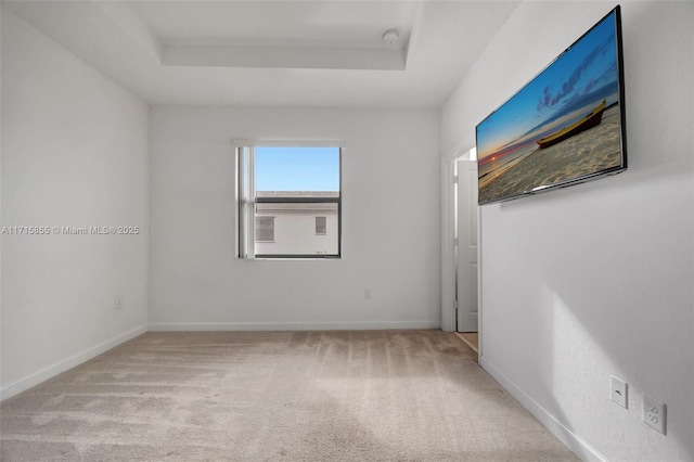 unfurnished room featuring light carpet and a raised ceiling