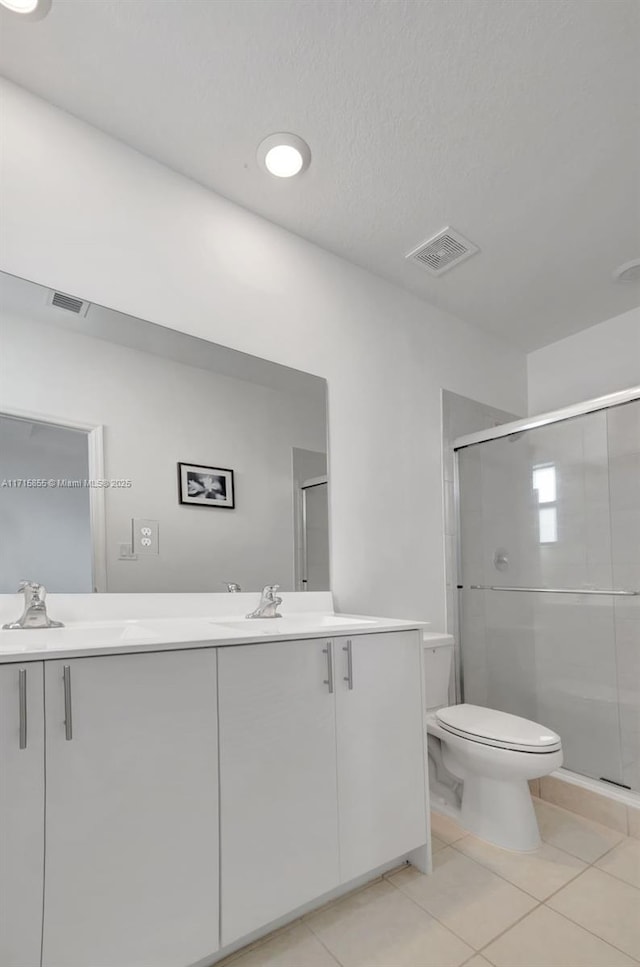 bathroom featuring toilet, vanity, tile patterned floors, and a shower with door