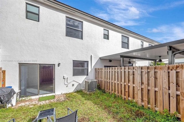 rear view of property with a lawn, central AC, and ceiling fan