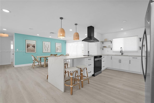 kitchen featuring a breakfast bar area, white cabinetry, electric range oven, island range hood, and decorative light fixtures