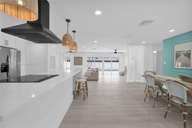 kitchen with pendant lighting, white cabinetry, island exhaust hood, light stone counters, and stainless steel refrigerator with ice dispenser