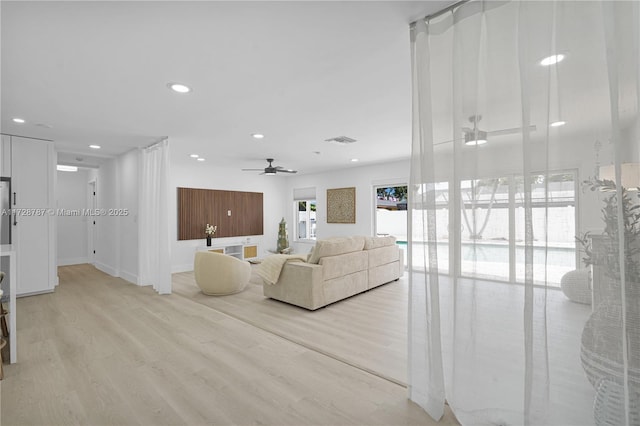 living room with ceiling fan and light hardwood / wood-style flooring