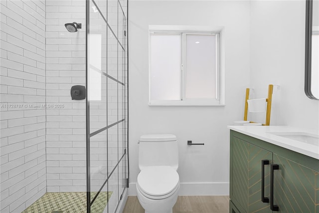 bathroom with a tile shower, vanity, and toilet