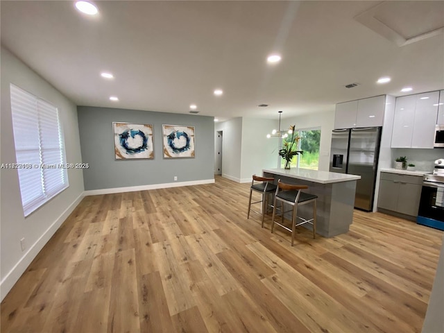 kitchen featuring pendant lighting, white cabinets, a kitchen island, stainless steel appliances, and a breakfast bar area