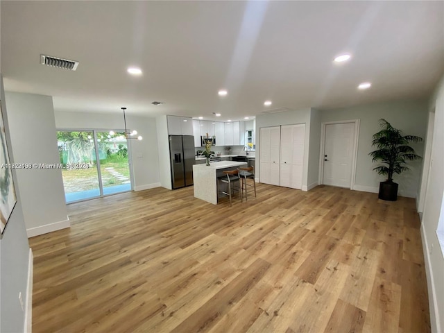 kitchen featuring a kitchen island, hanging light fixtures, a breakfast bar area, stainless steel appliances, and white cabinets