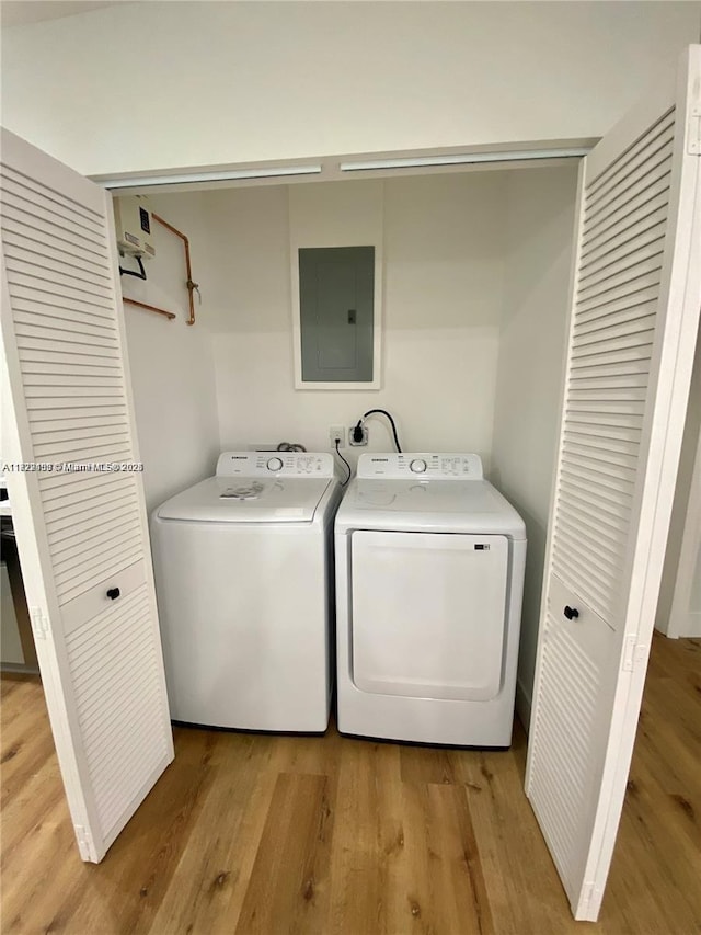 laundry area featuring washing machine and dryer, electric panel, and light wood-type flooring