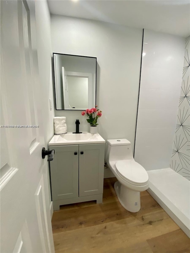 bathroom featuring a shower, hardwood / wood-style floors, toilet, and vanity