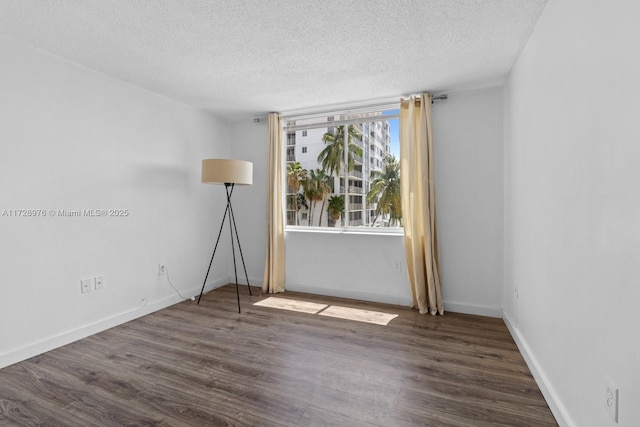 empty room with dark hardwood / wood-style flooring and a textured ceiling