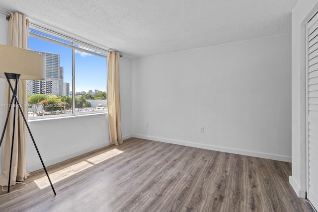 unfurnished room featuring wood-type flooring and a textured ceiling