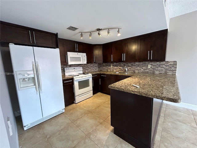 kitchen with kitchen peninsula, tasteful backsplash, white appliances, dark stone countertops, and dark brown cabinets