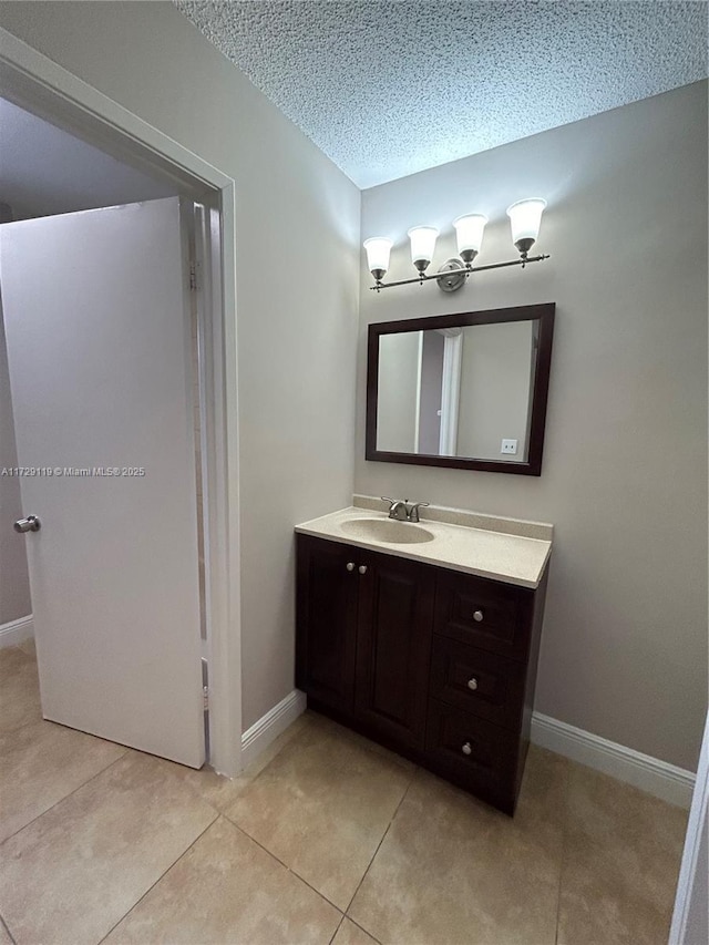 bathroom with a textured ceiling, tile patterned floors, and vanity