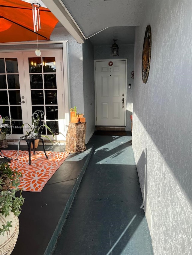 view of exterior entry featuring french doors and stucco siding