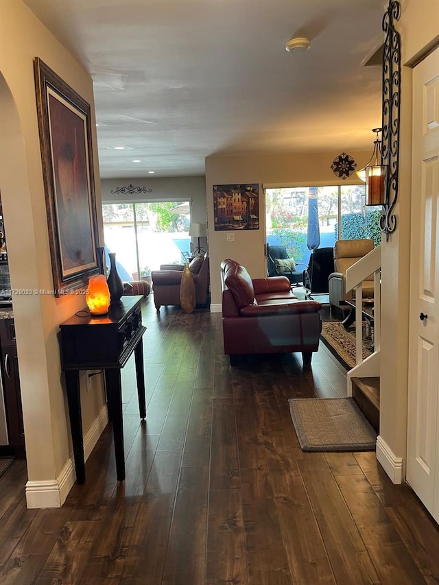 living area featuring baseboards, arched walkways, and dark wood-style floors