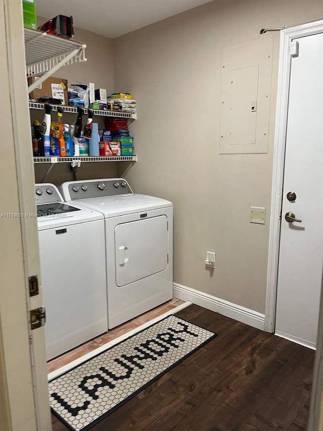 washroom with baseboards, electric panel, laundry area, washing machine and clothes dryer, and wood finished floors