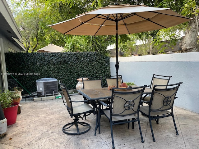 view of patio featuring central AC, fence, and outdoor dining area