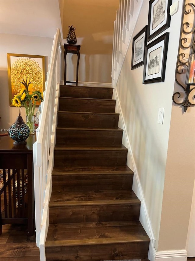 staircase with baseboards and wood finished floors