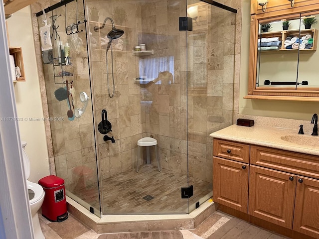 bathroom featuring a shower with shower door, toilet, and vanity