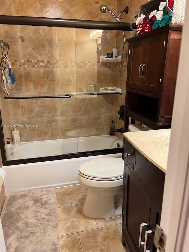 full bath featuring bath / shower combo with glass door, vanity, toilet, and tile patterned flooring
