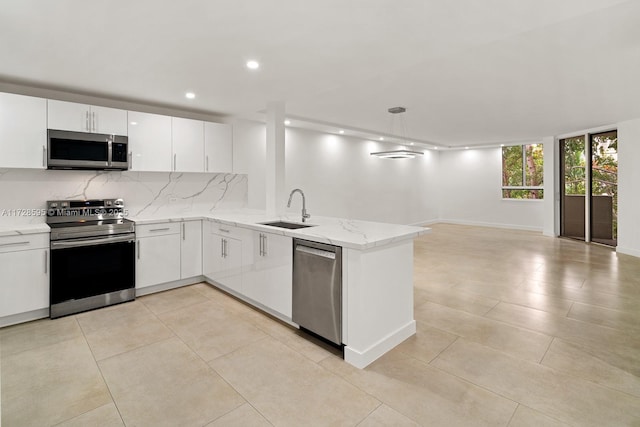 kitchen featuring kitchen peninsula, sink, white cabinetry, stainless steel appliances, and light stone counters