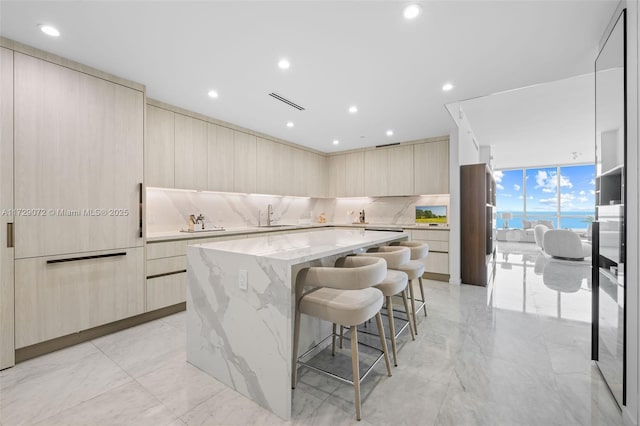 kitchen with a kitchen island, tasteful backsplash, sink, floor to ceiling windows, and a breakfast bar