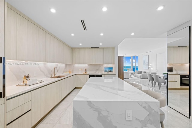 kitchen with backsplash, a center island, a breakfast bar, sink, and light stone countertops