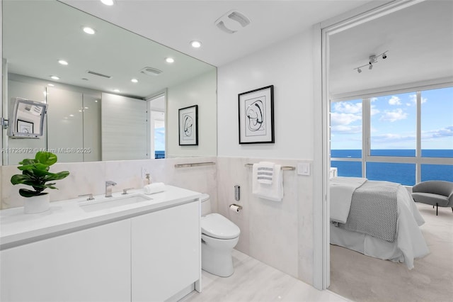 bathroom with toilet, tile walls, a water view, and vanity