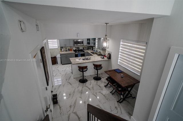 kitchen featuring gray cabinets, pendant lighting, tasteful backsplash, kitchen peninsula, and stainless steel appliances