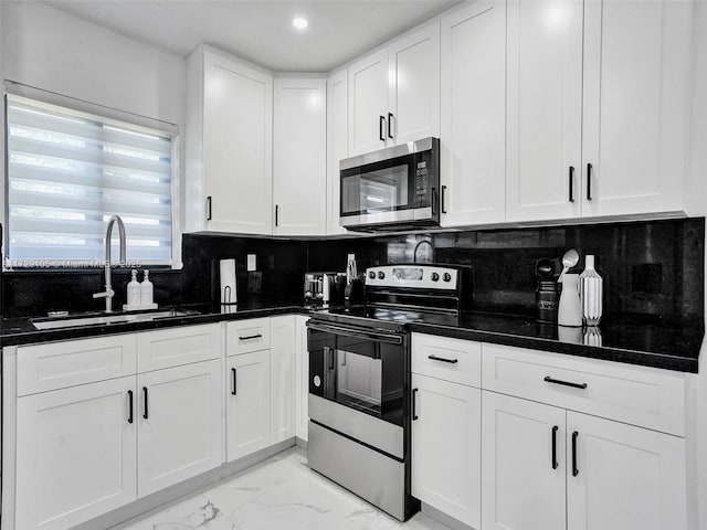 kitchen with white cabinets, appliances with stainless steel finishes, sink, and backsplash