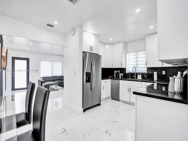 kitchen with sink, white cabinets, decorative backsplash, stainless steel appliances, and a healthy amount of sunlight