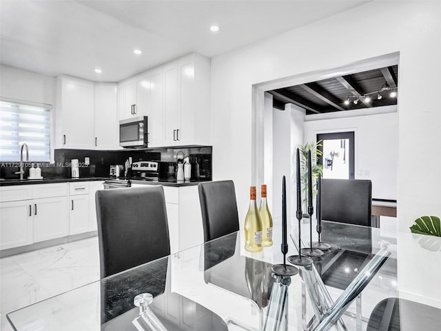 kitchen featuring sink, backsplash, stainless steel appliances, and white cabinets