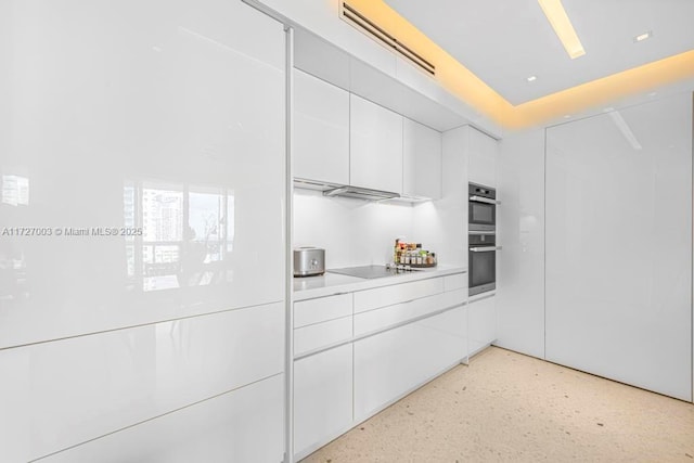 kitchen with stainless steel double oven, black electric cooktop, and white cabinetry