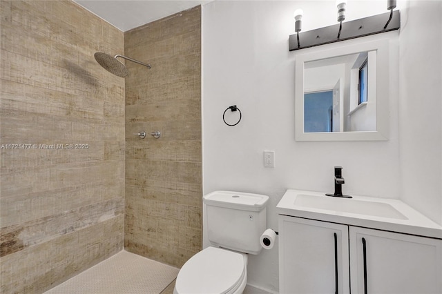 bathroom with toilet, vanity, and a tile shower